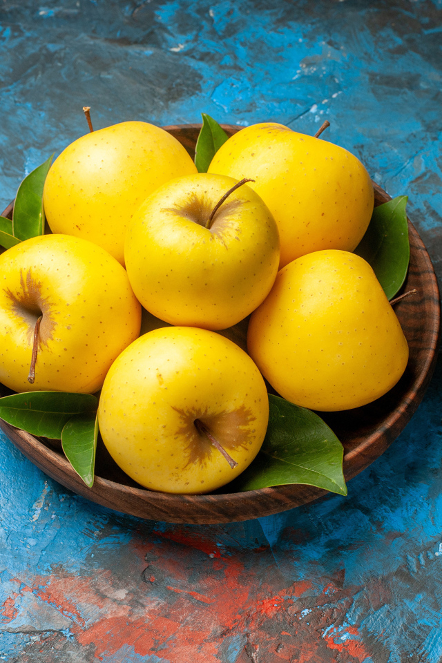 Деревянная тарелка с яблоками на столе