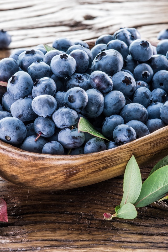 Деревянная тарелка с ягодами черники на столе