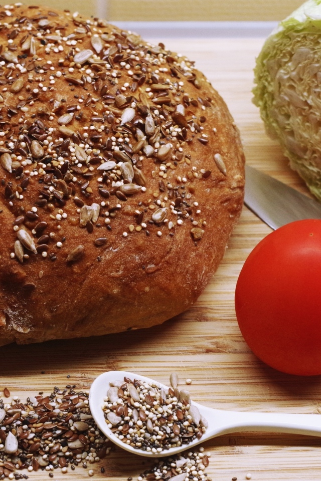 Буханка хлеба на столе с капустой и помидором