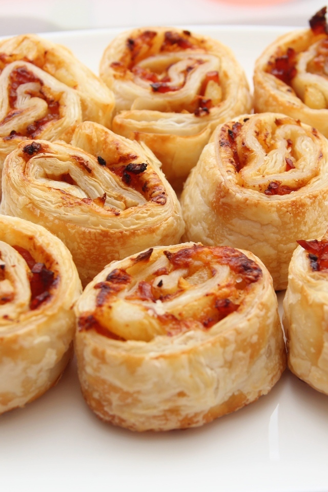 Рулетики из слоеного теста с ветчиной на тарелке