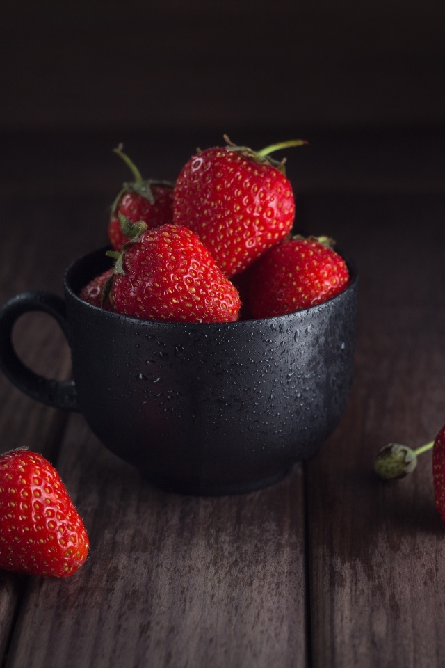 Черная чашка с красными ягодами клубники