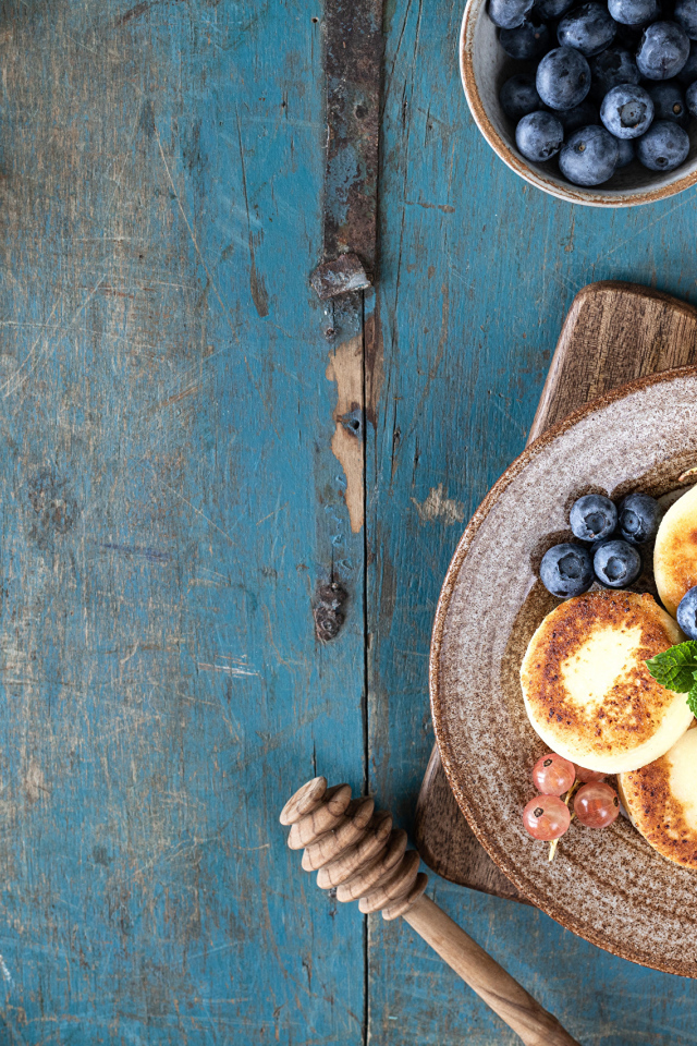 Сырники с ягодами черники на тарелке с медом