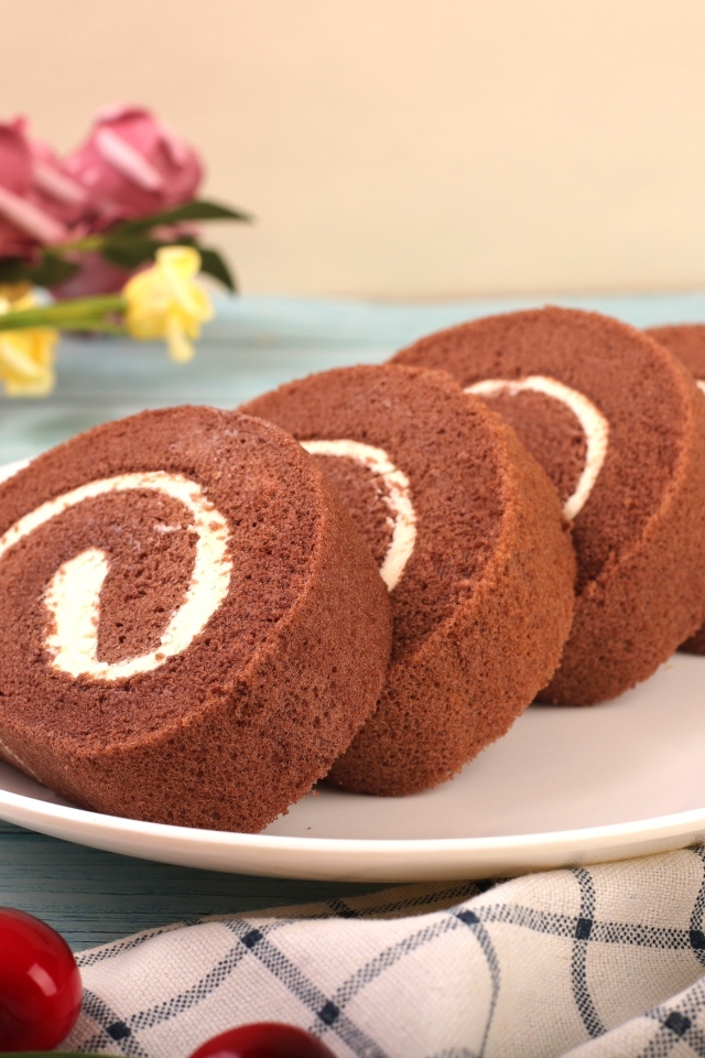 Шоколадный бисквитный рулет с кремом на тарелке
