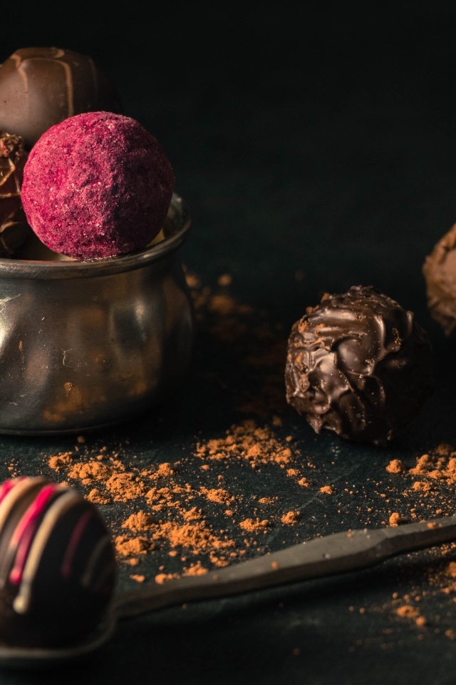 Шоколадные конфеты с железной чашкой на черном фоне