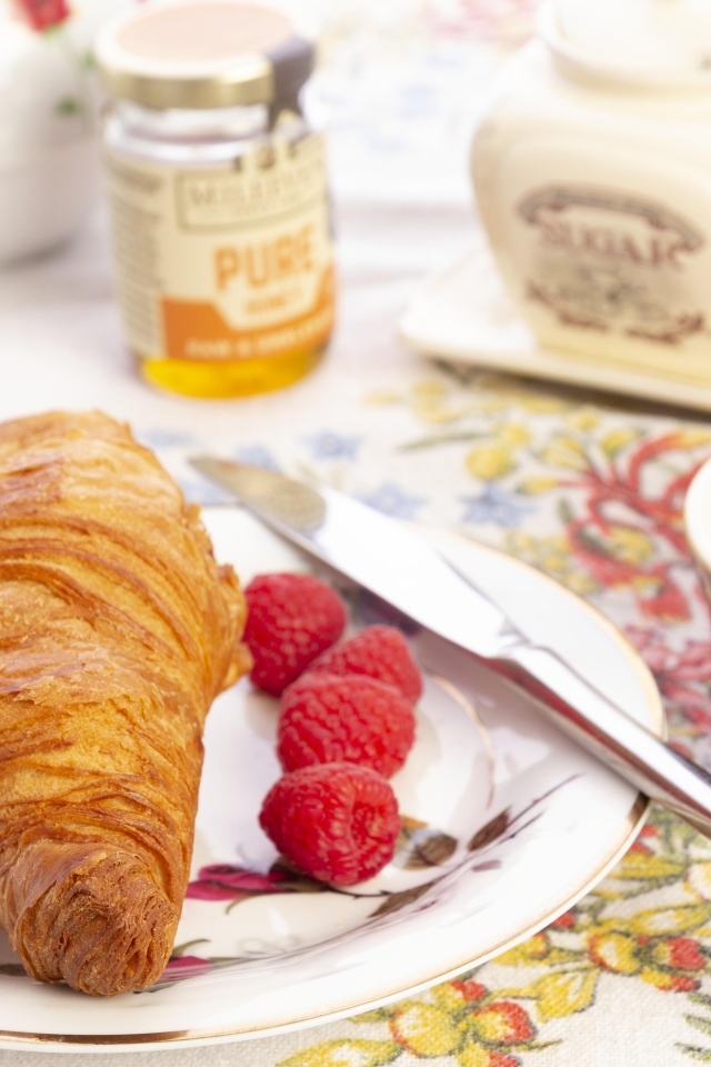 Круассан с ягодами малины на тарелке