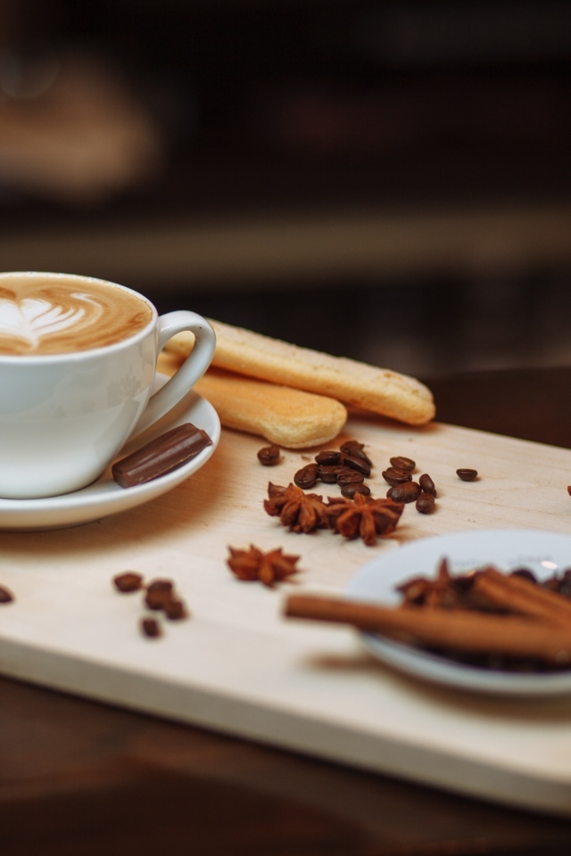 Чашка кофе на доске с печеньем и специями