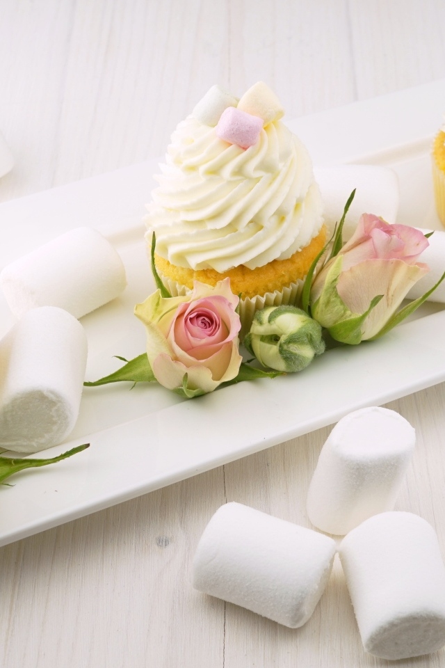 Капкейки с кремом на тарелке с розами и маршмеллоу