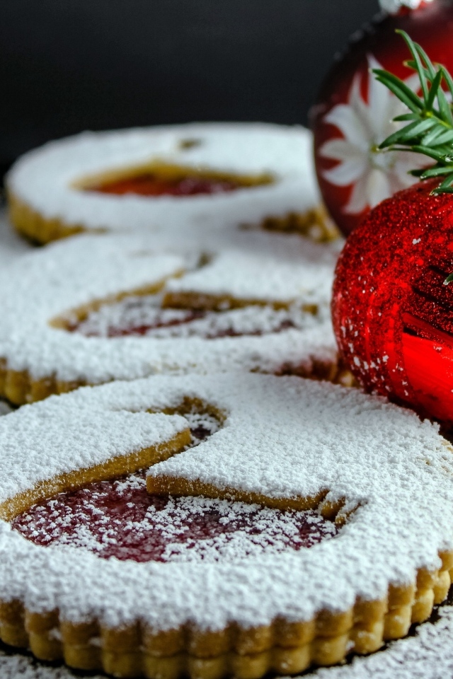 Вкусное сладкое печенье в сахарной пудре на столе с елочными игрушками