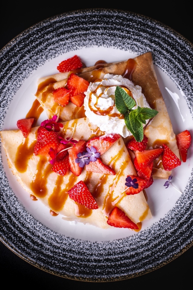 Вкусные сладкие блинчики на тарелке с ягодами