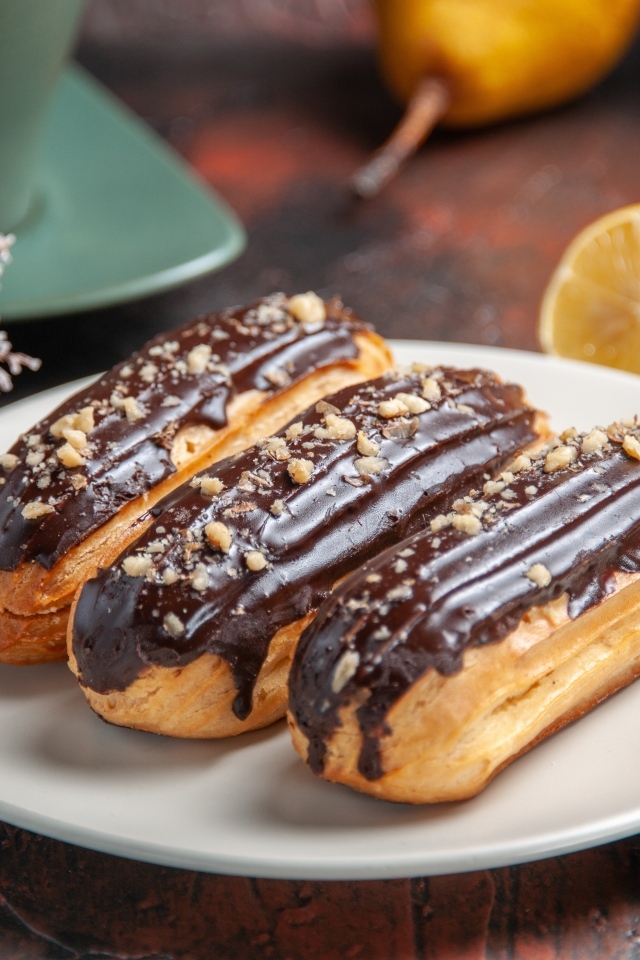 Эклеры на тарелке с корицей и апельсинами