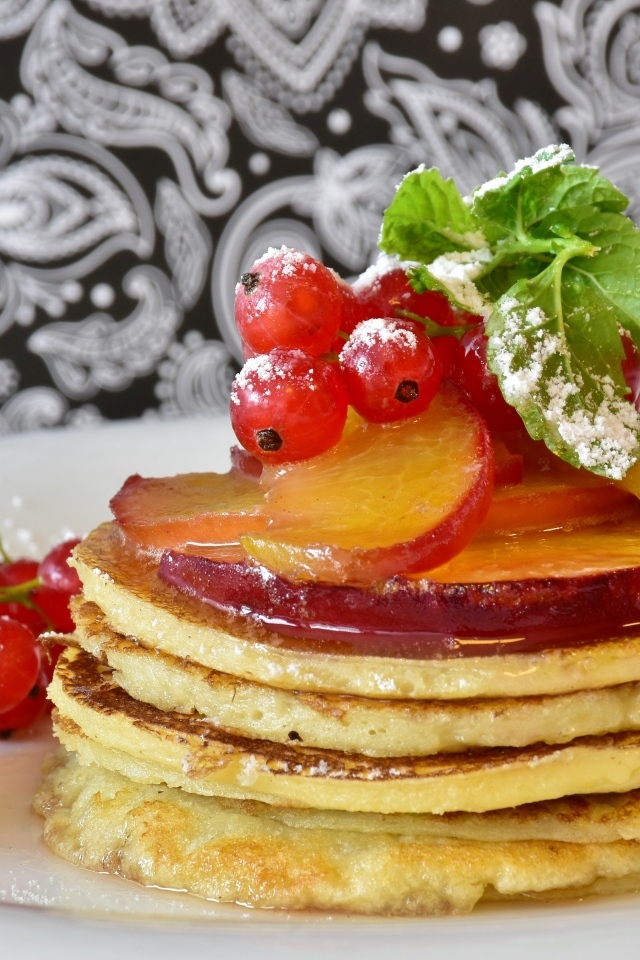 Оладьи на тарелке с ягодами смородины  и сливы