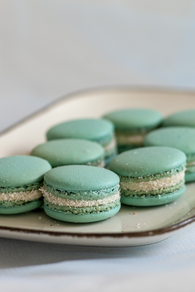 Зеленый десерт макаронс на большой тарелке на столе