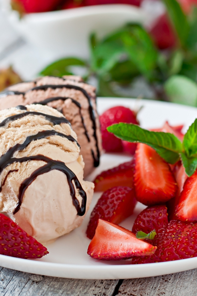 Шарики мороженого на тарелке с кусочками клубники