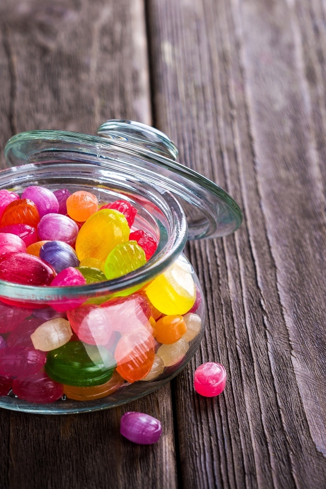 Разноцветные конфеты в стеклянной банке на столе