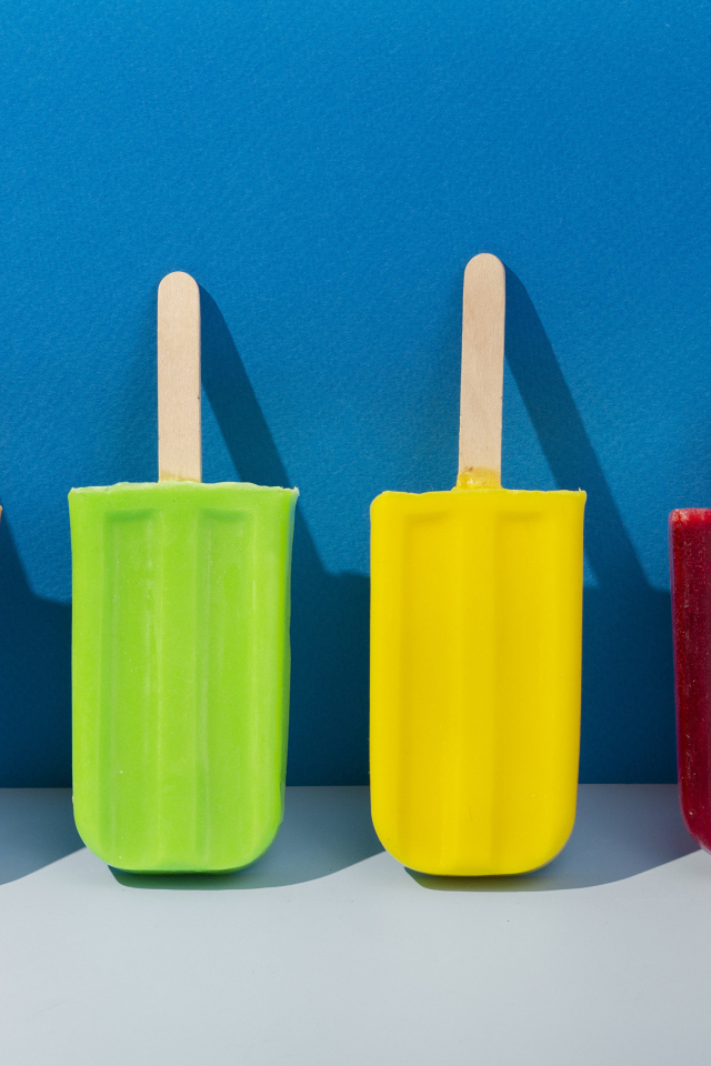 Разноцветное фруктовое мороженое на фоне голубой стены