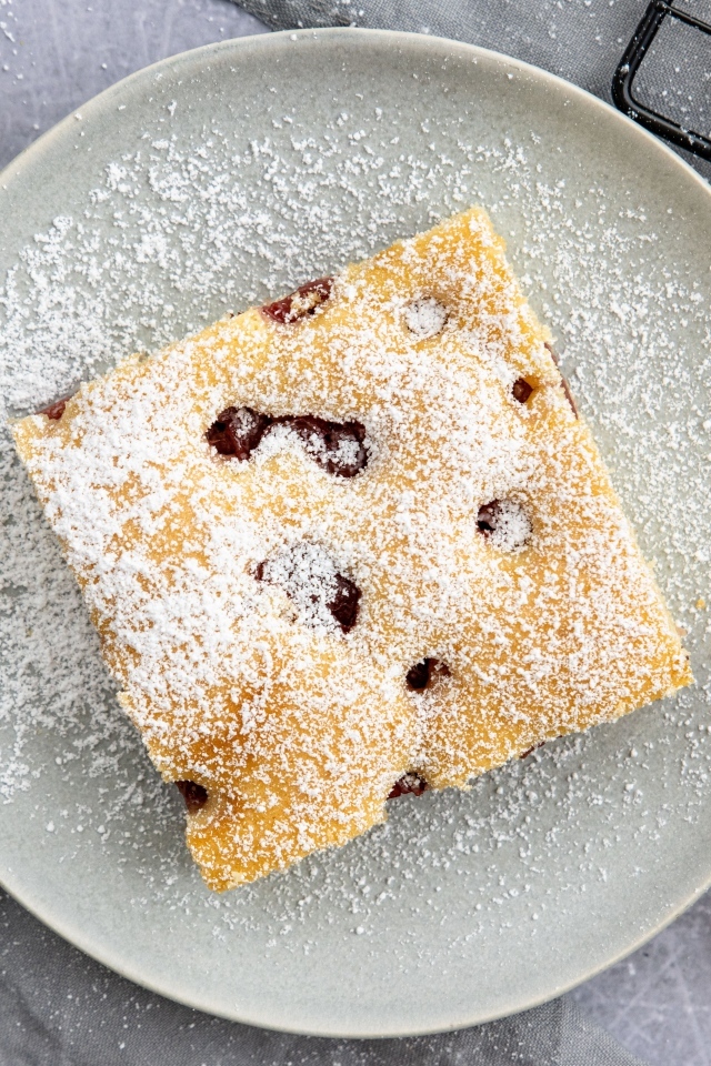 Кусок вишневого пирога на тарелке с сахарной пудрой