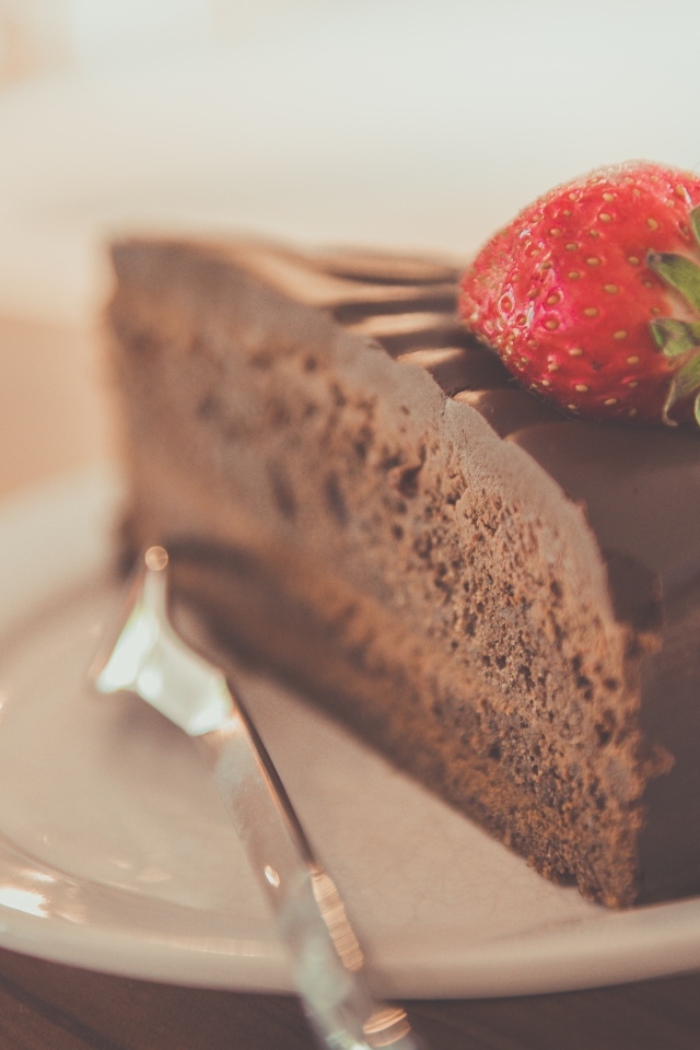 Кусок шоколадного торта с клубникой на тарелке