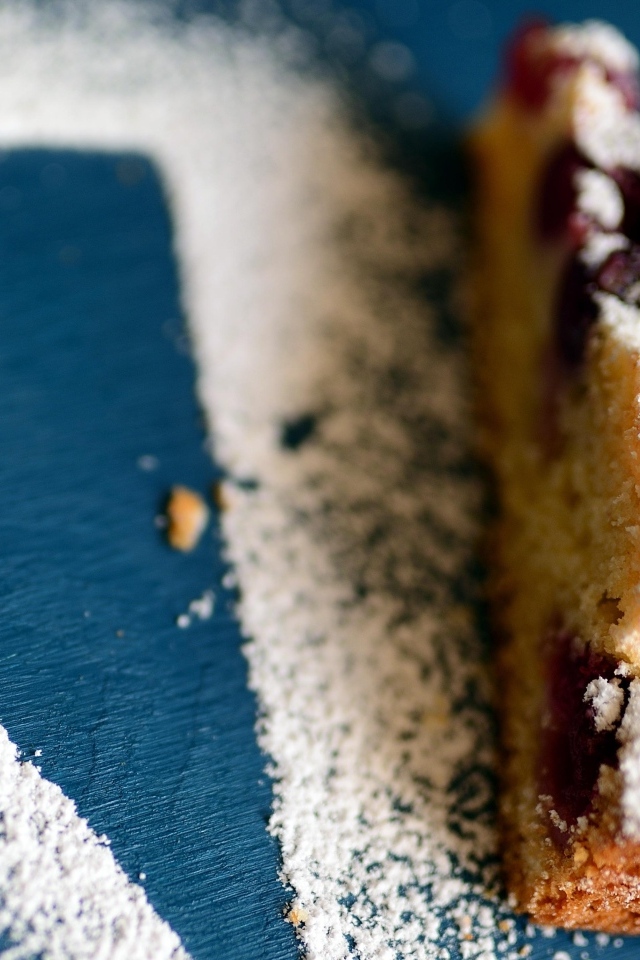 Кусок пирога с ягодами на столе с сахарной пудрой