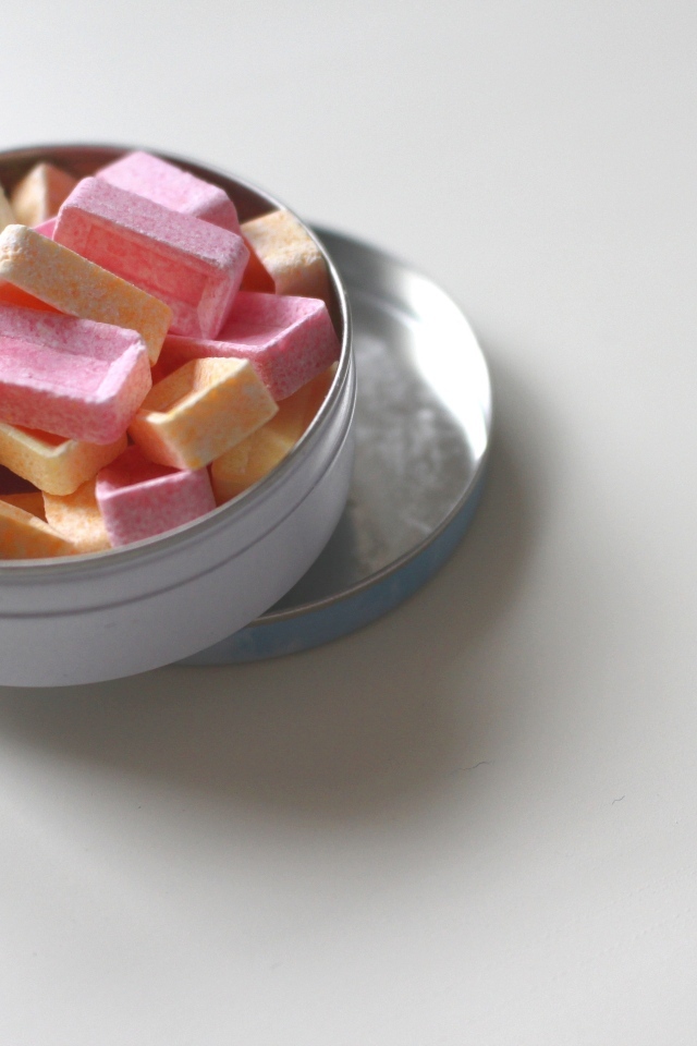 Розовые и оранжевые конфеты в коробке на сером фоне