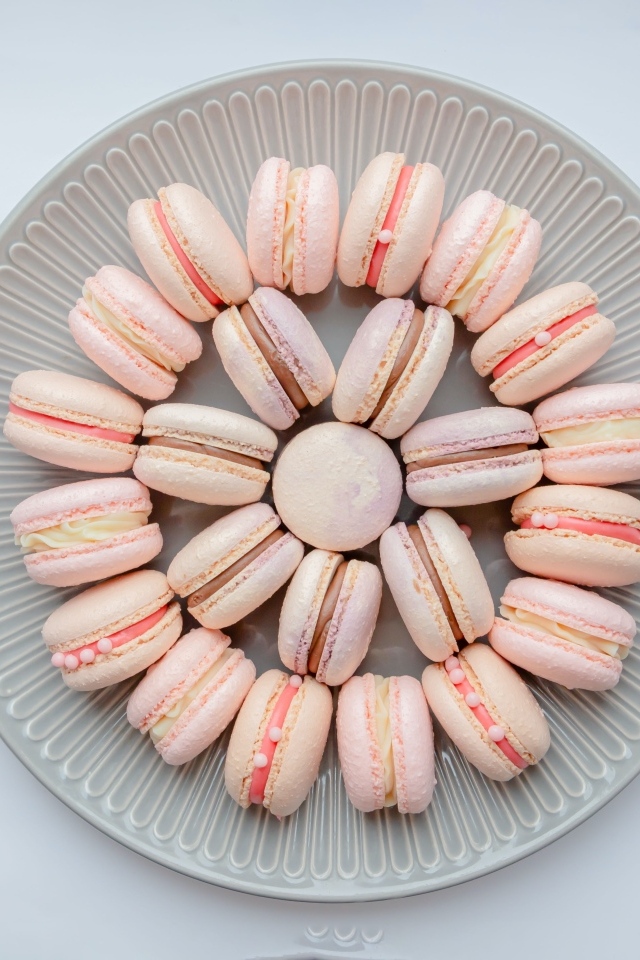 Розовый десерт макарон на большой тарелке
