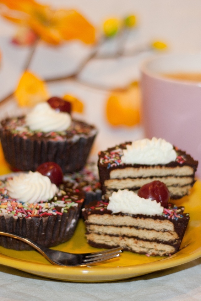 Сладкие вкусные пирожные на столе с чашкой чая и цветами