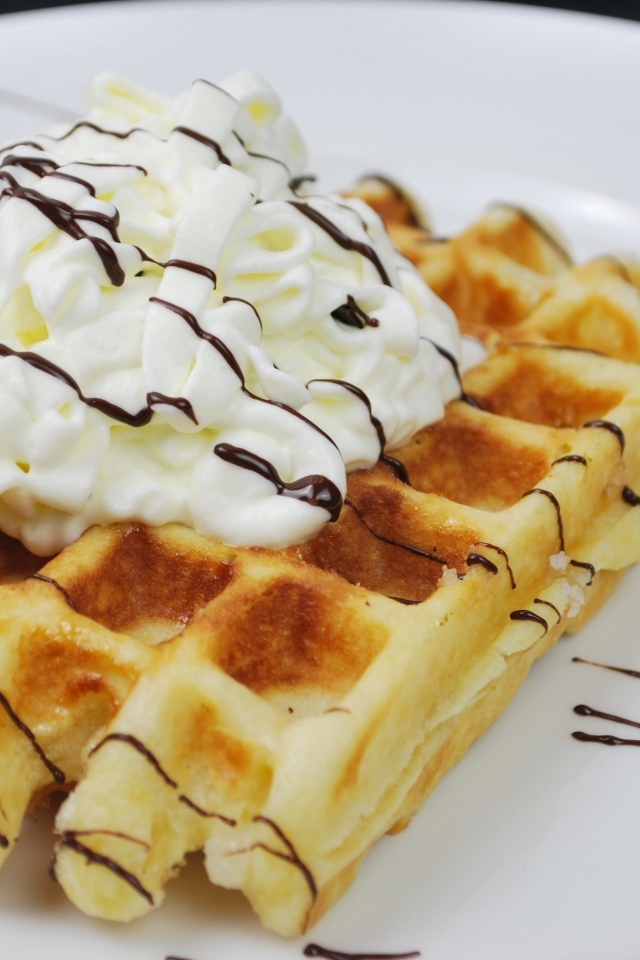 Сладкая вафля со сливками на белой тарелке