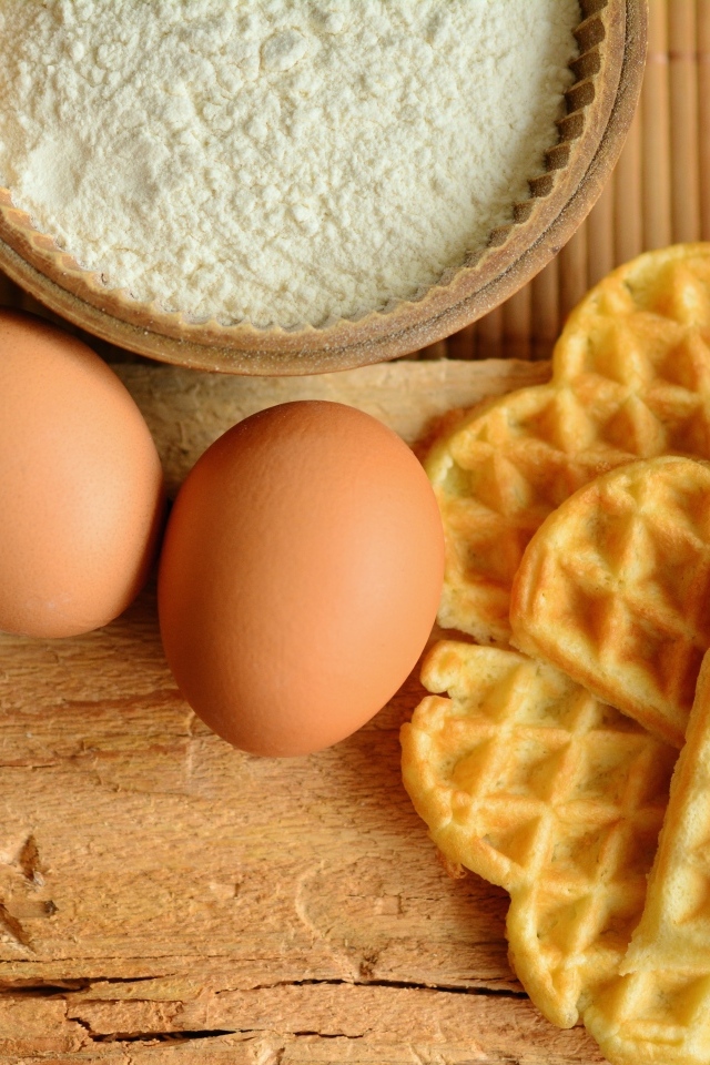 Сладкие вафли с яйцами и мукой на столе