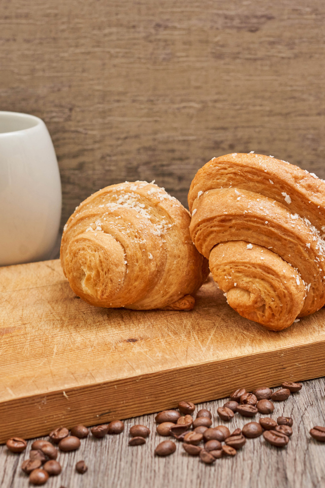 Два круассана на доске с кофейными зернами