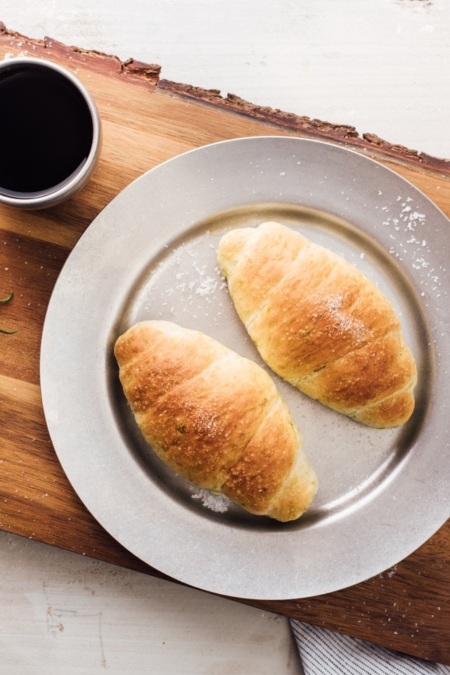 Два круассана на тарелке с чашкой кофе