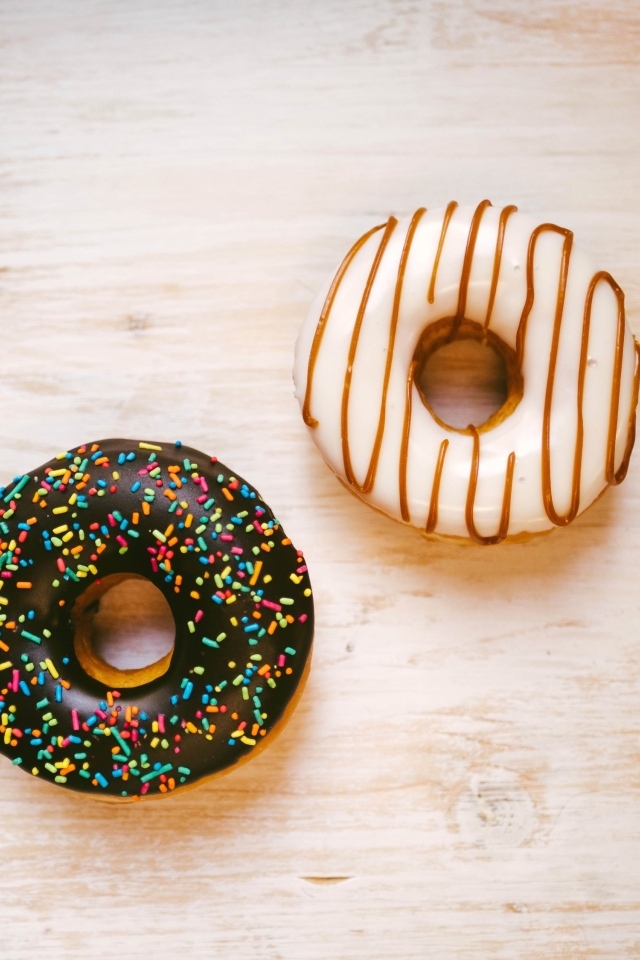 Два пончика в глазури на деревянном столе