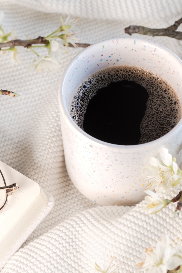 Чашка кофе с цветущей веткой на столе