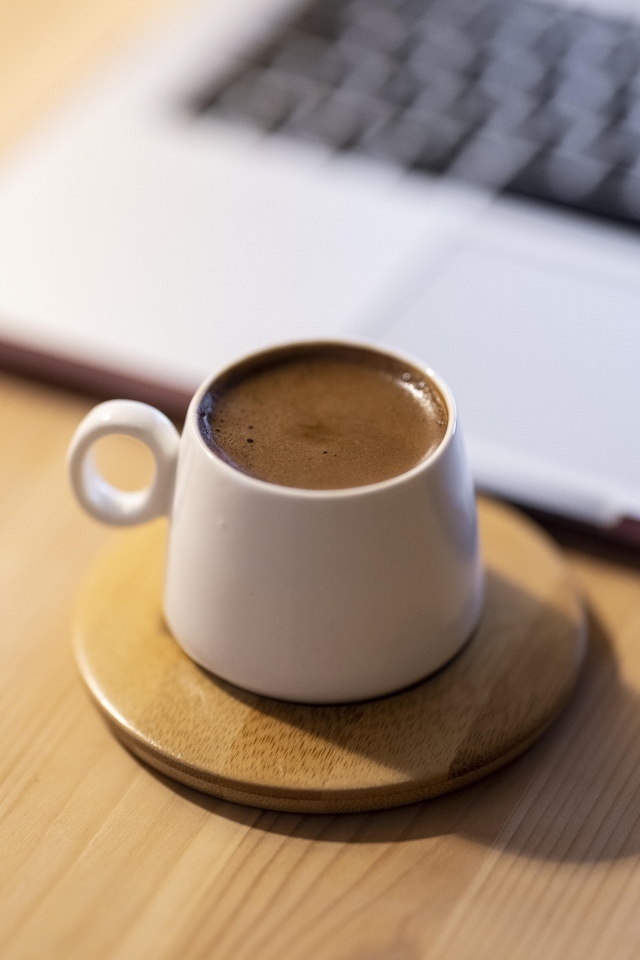 Чашка крепкого кофе стоит у ноутбука