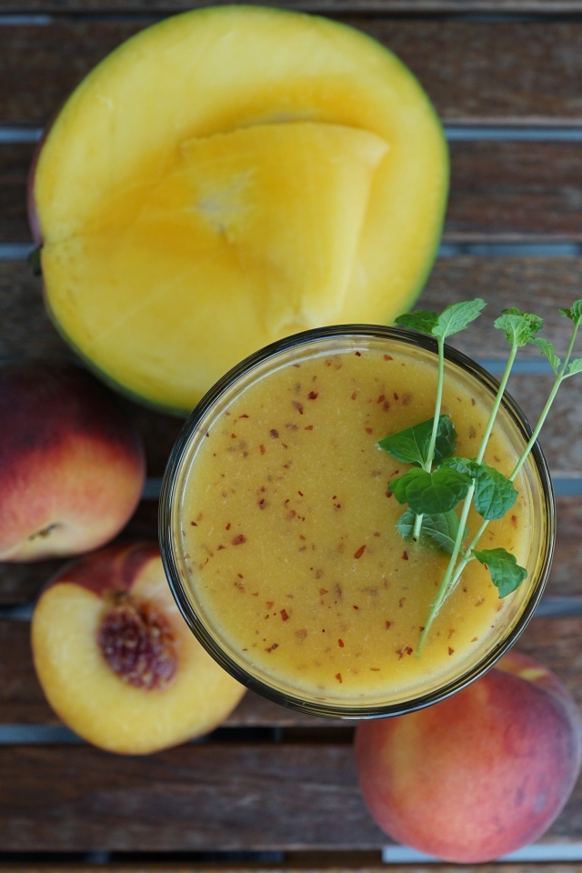 Коктейль с веточкой мяты на столе с фруктами