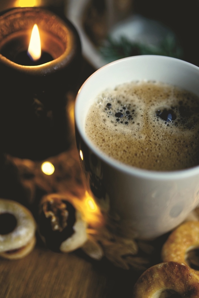 Чашка кофе на столе со свечой и печеньем