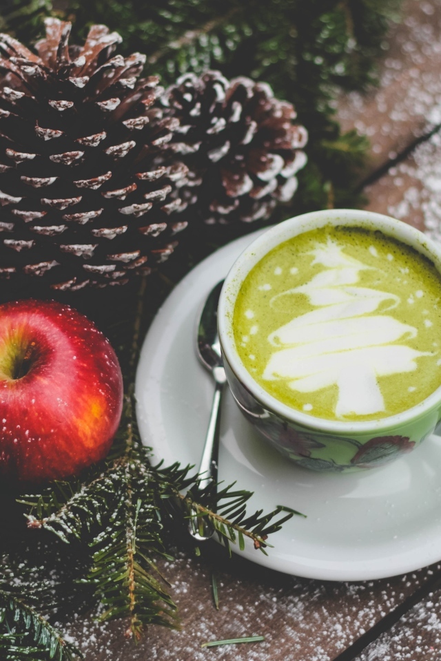 Чашка кофе на столе с яблоками и шишками