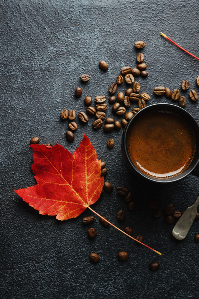 Чашка кофе на столе с зернами и желтыми листьями