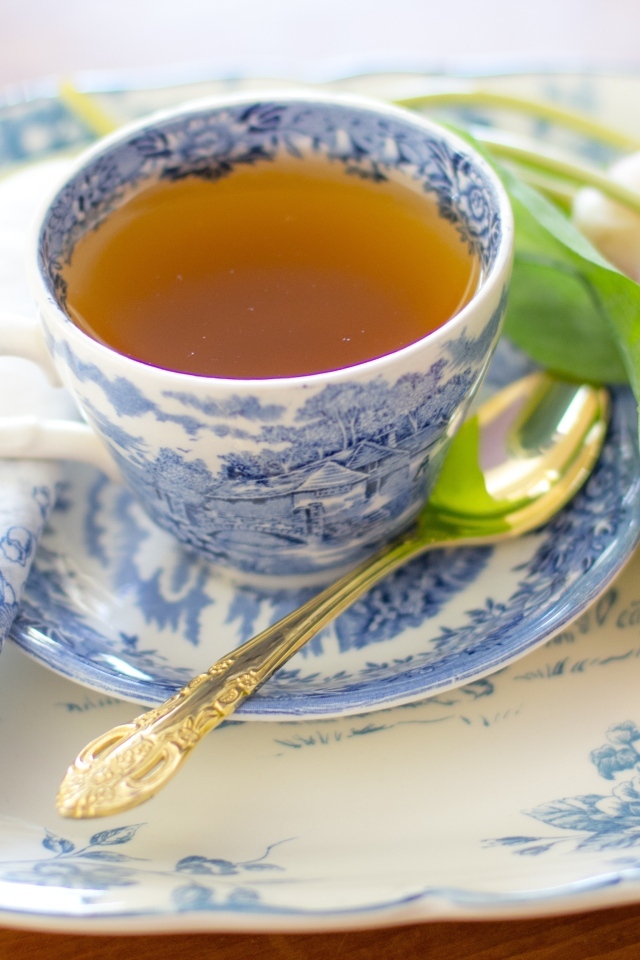 Чашка чая на тарелке с розовыми тюльпанами