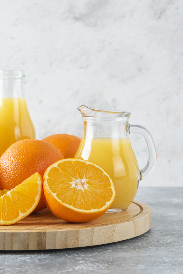 Свежевыжатый сок на столе с апельсинами