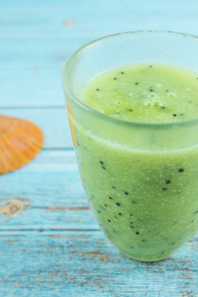 Фруктовый зеленый смузи на голубом столе
