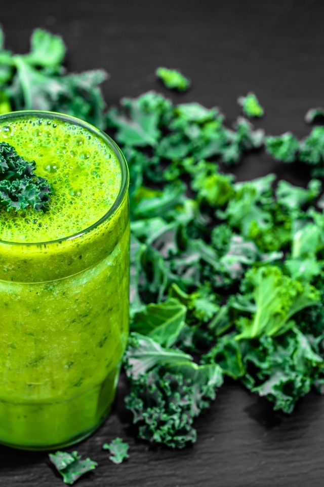 Бокал с зеленым смузи с листьями