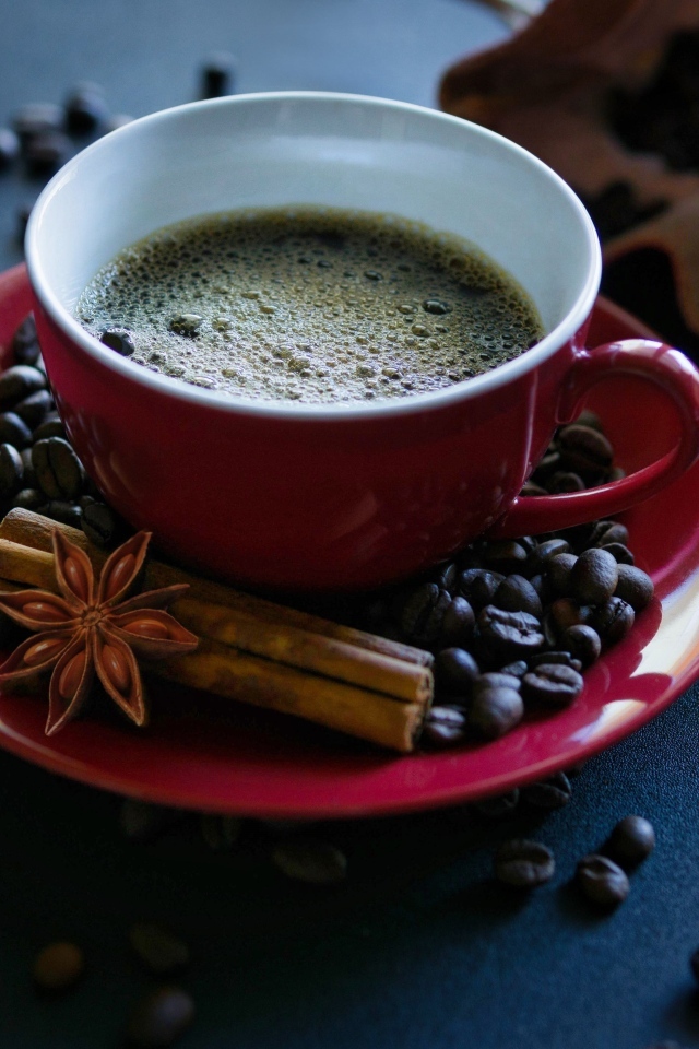 Красная чашка кофе на столе со специями и зернами