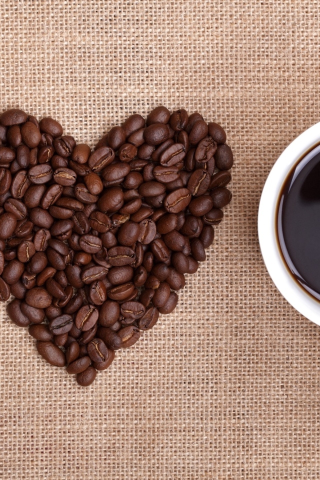 Ложка, сердце из кофейных зерен и белая кружка на столе