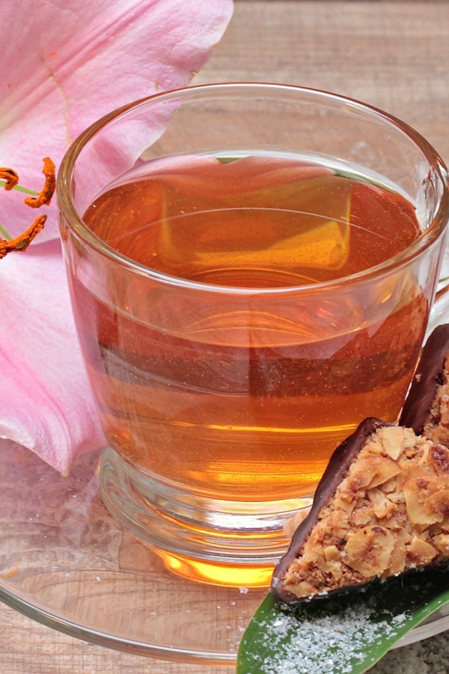 Чай на столе с розовой лилией и конфетами