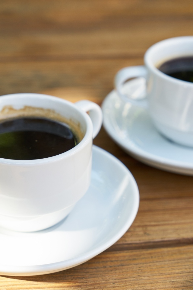 Две белые чашки кофе на столе 