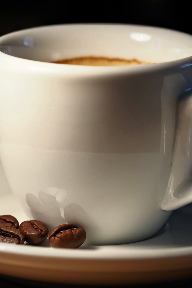 Белая чашка кофе с зернами крупным планом