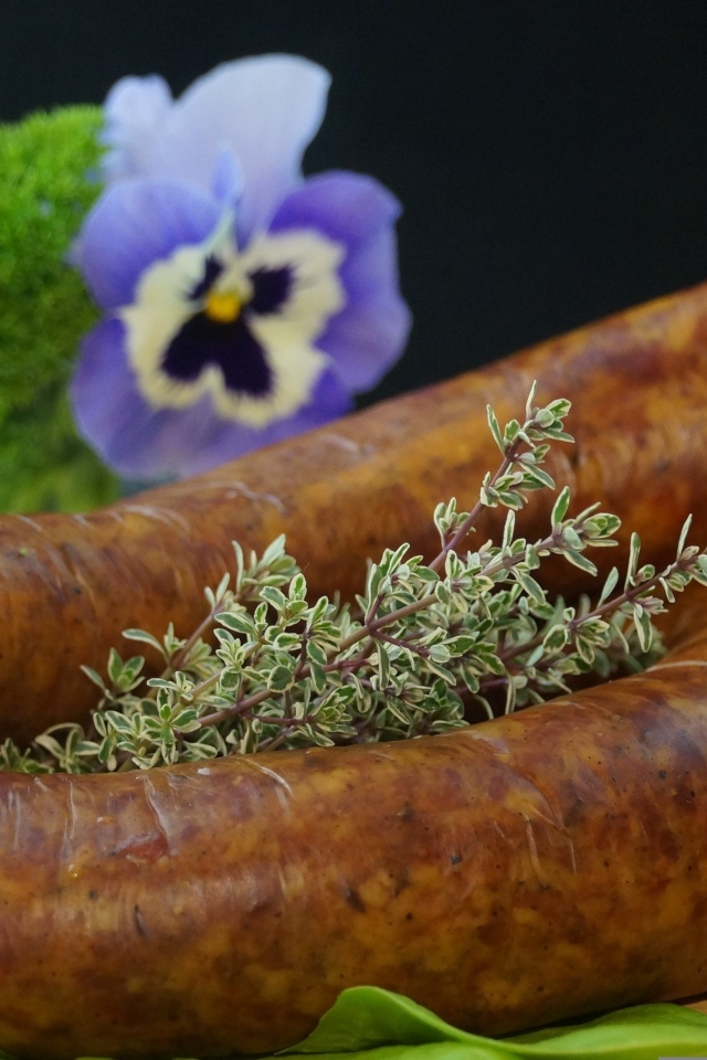 Свежая домашняя колбаса на столе с цветами