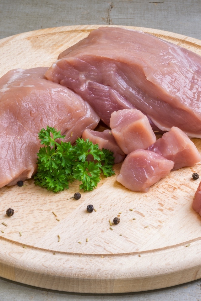 Свежая свинина на разделочной доске с петрушкой