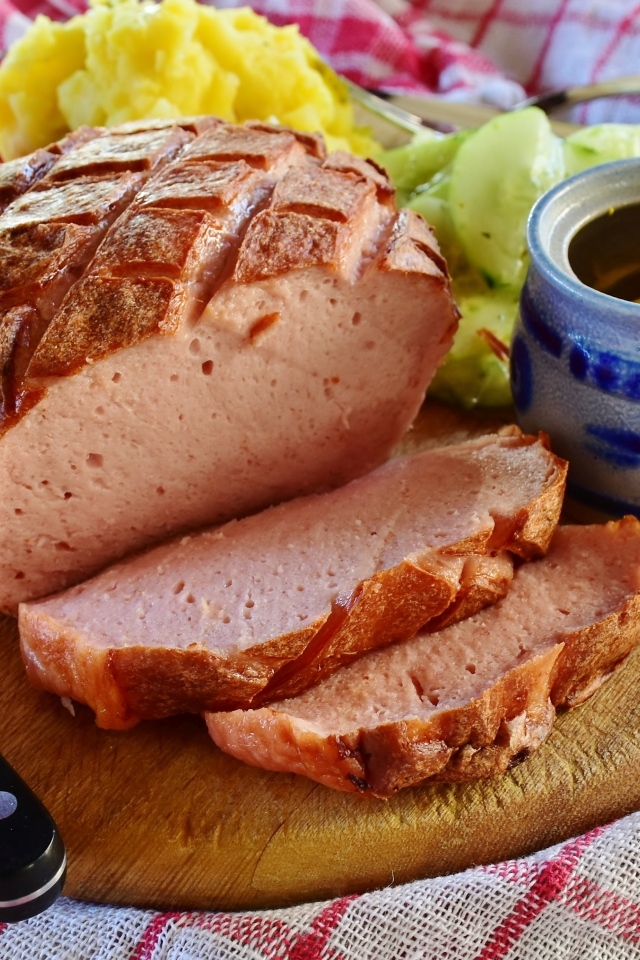 Мясной хлеб на столе с ножом и овощами