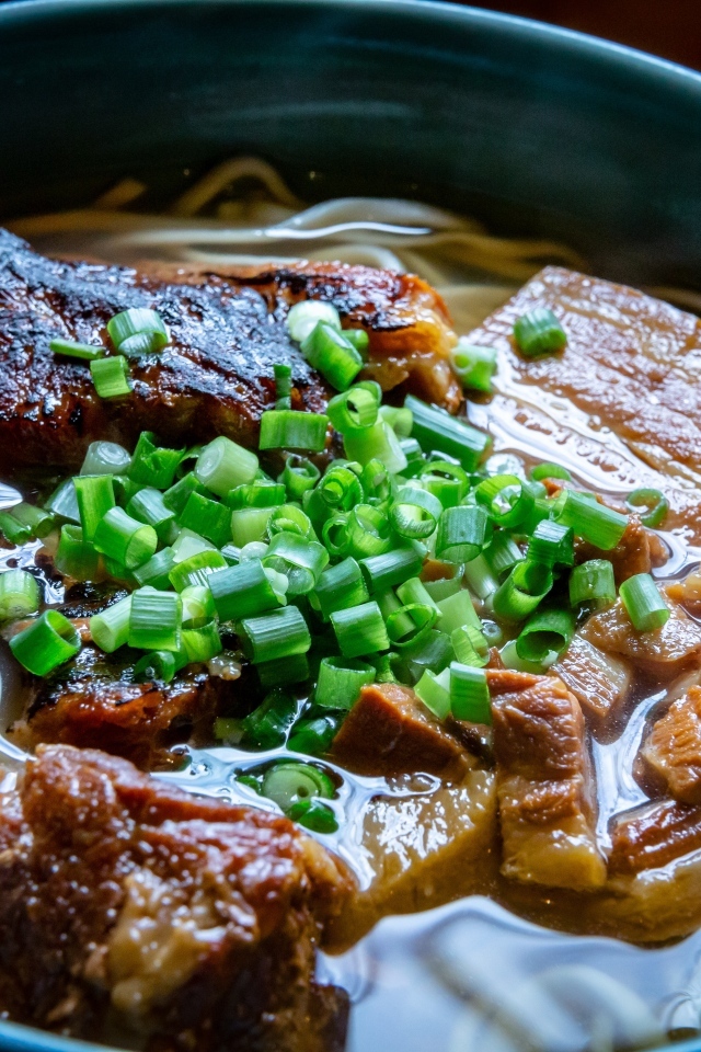 Лапша с мясом и зеленым луком в тарелке