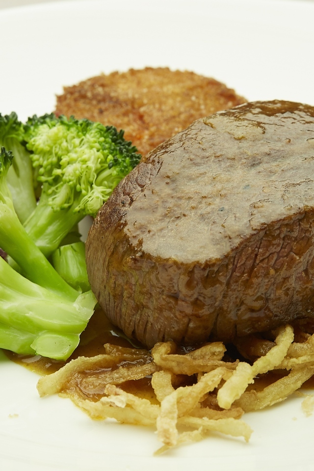 Кусок мяса на тарелке с овощами